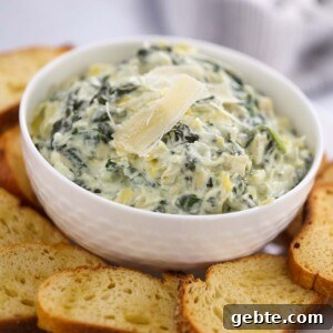 Slow Cooker Spinach and Artichoke Dip Recipe for Parties 6 Crockpot spinach artichoke dip in a white bowl with baguette slices.