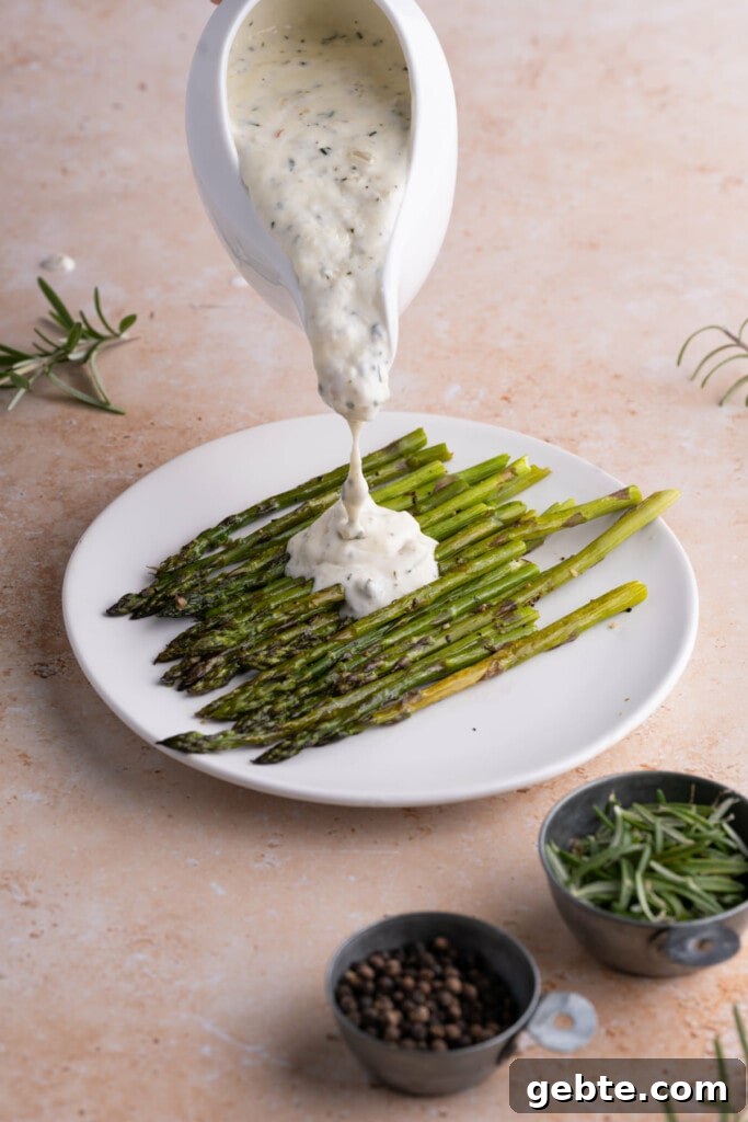 Pouring Shallot Cream Sauce over roasted asparagus