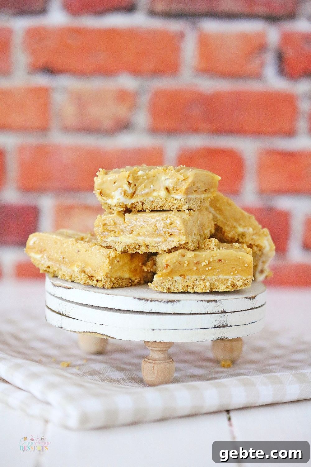 A few bars of peanut butter fudge with cream cheese and a graham crust, on a dessert serving plate