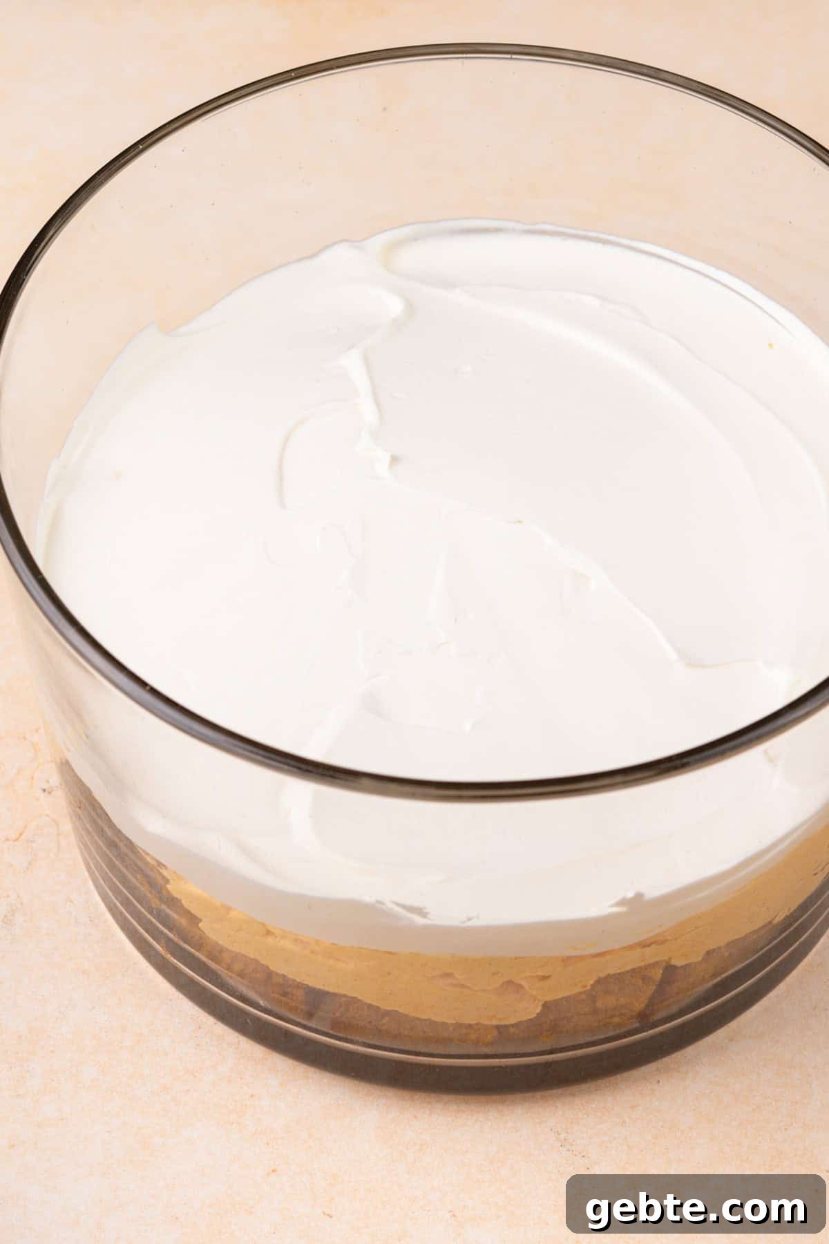 Whipped topping spread on top of pumpkin filling in a trifle dish.