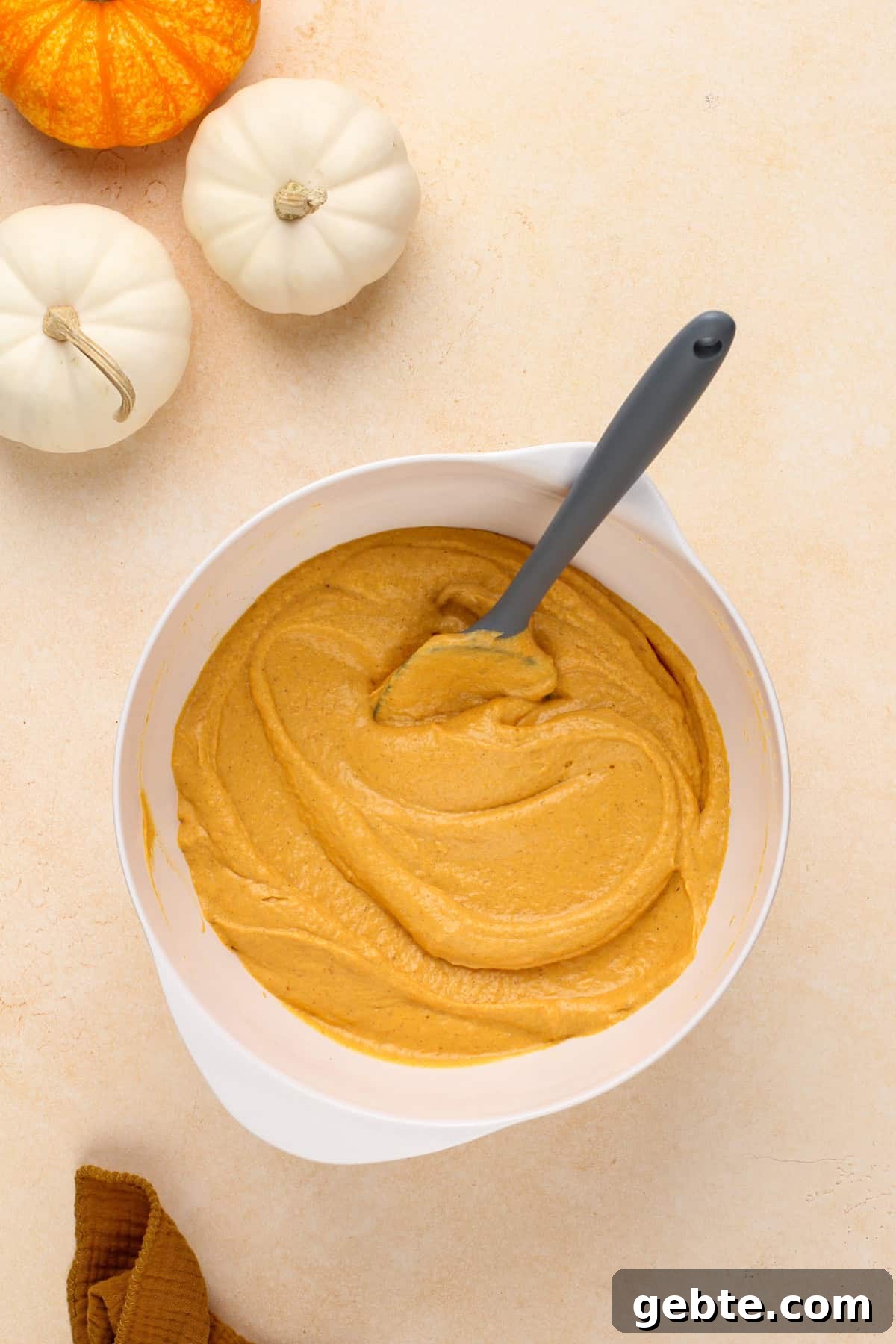 Pumpkin and cream cheese mixture being mixed in a white bowl.