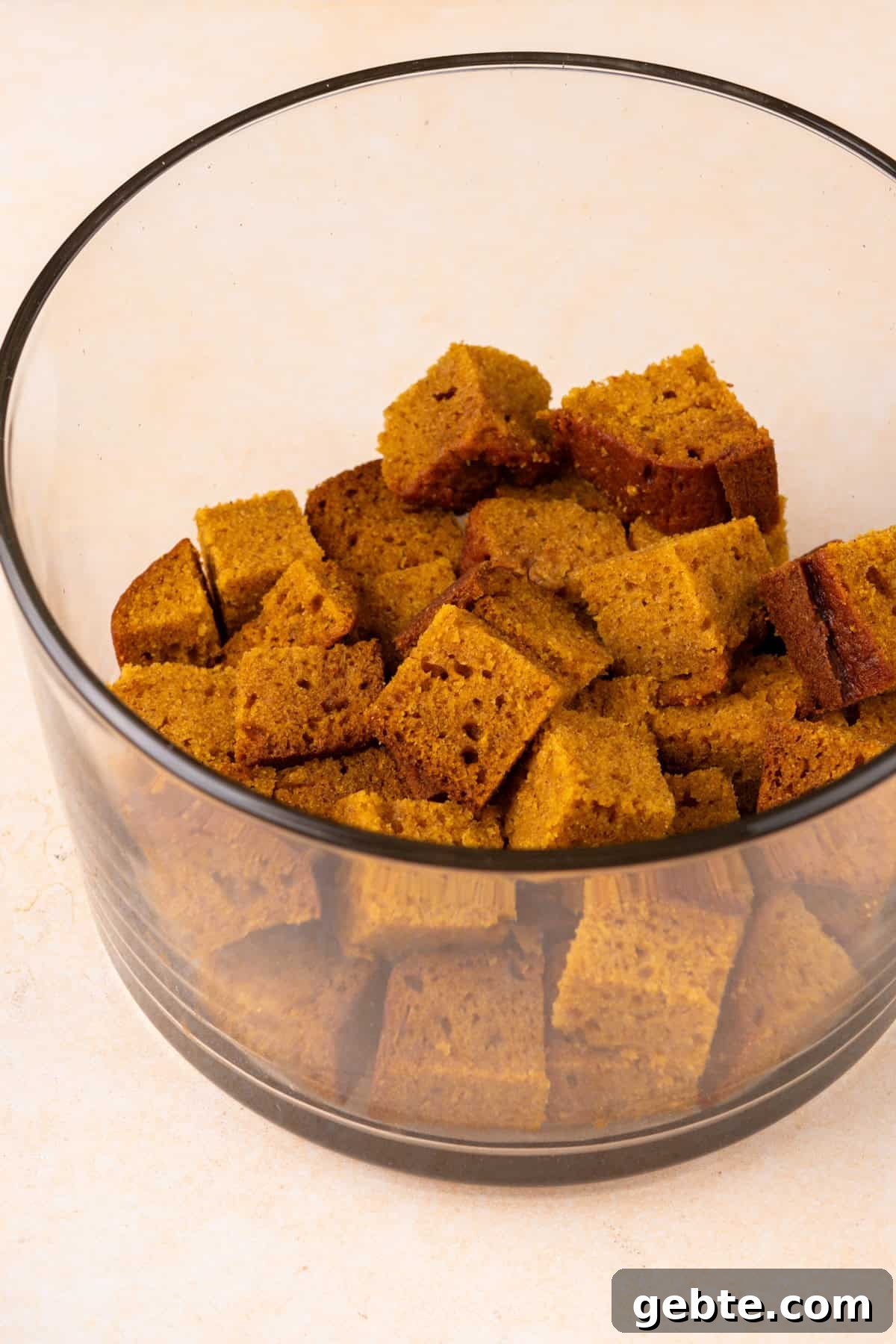 Cubes of pumpkin bread in the bottom of a trifle dish.