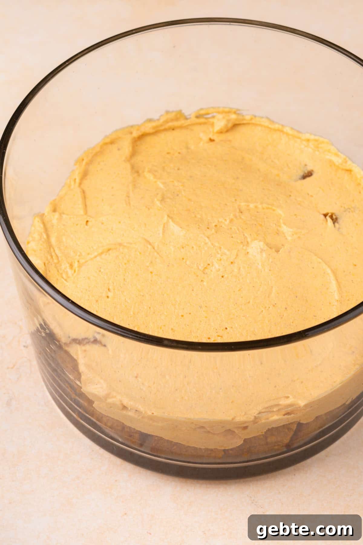 Pumpkin cream cheese filling spread on top of pumpkin bread in a trifle dish.