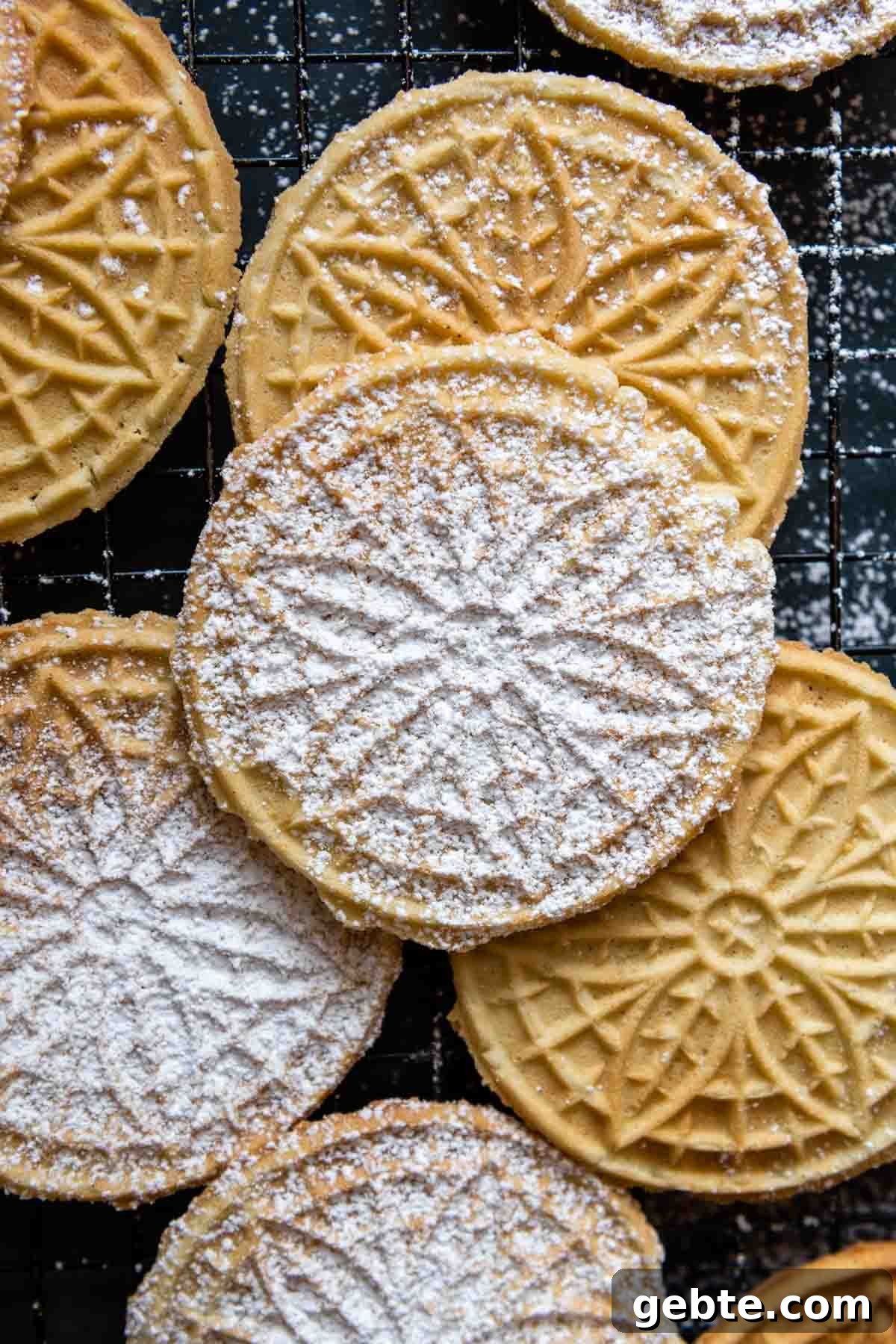 Crisp Gluten-Free Pizzelle Recipe: Authentic Italian Cookies 7 overhead shot of pizzelles with powdered sugar on a cooling rack.