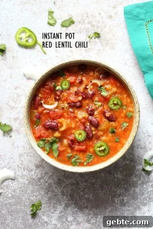 A bowl of instant pot red lentil chili on a white background with a turquoise napkin