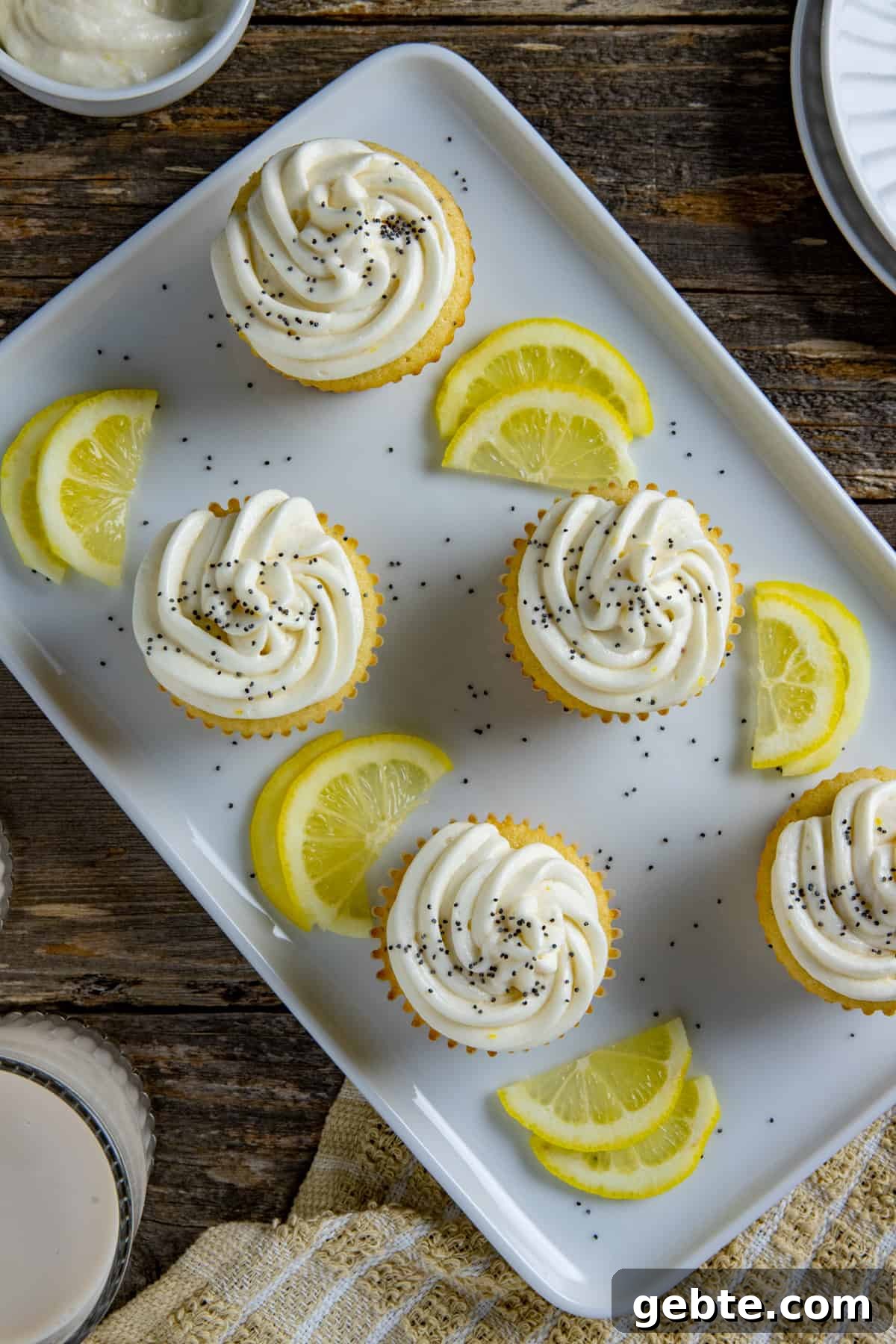 Frosted cupcakes on light blue serving platter with lemon slices as garnish.