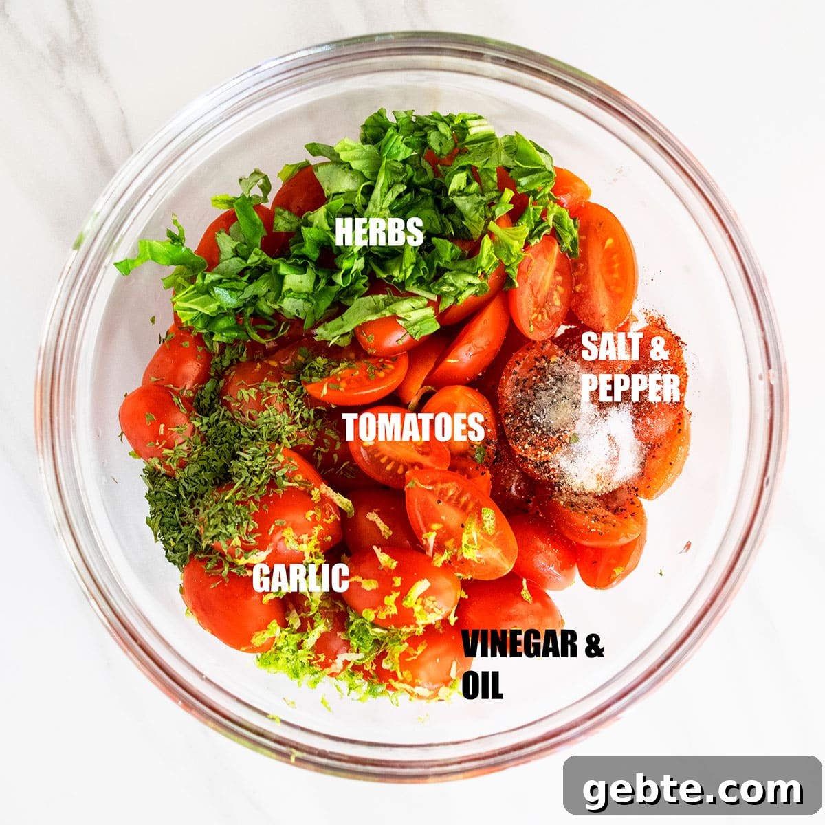 Ingredients in a glass bowl on white marble background ready to be tossed.
