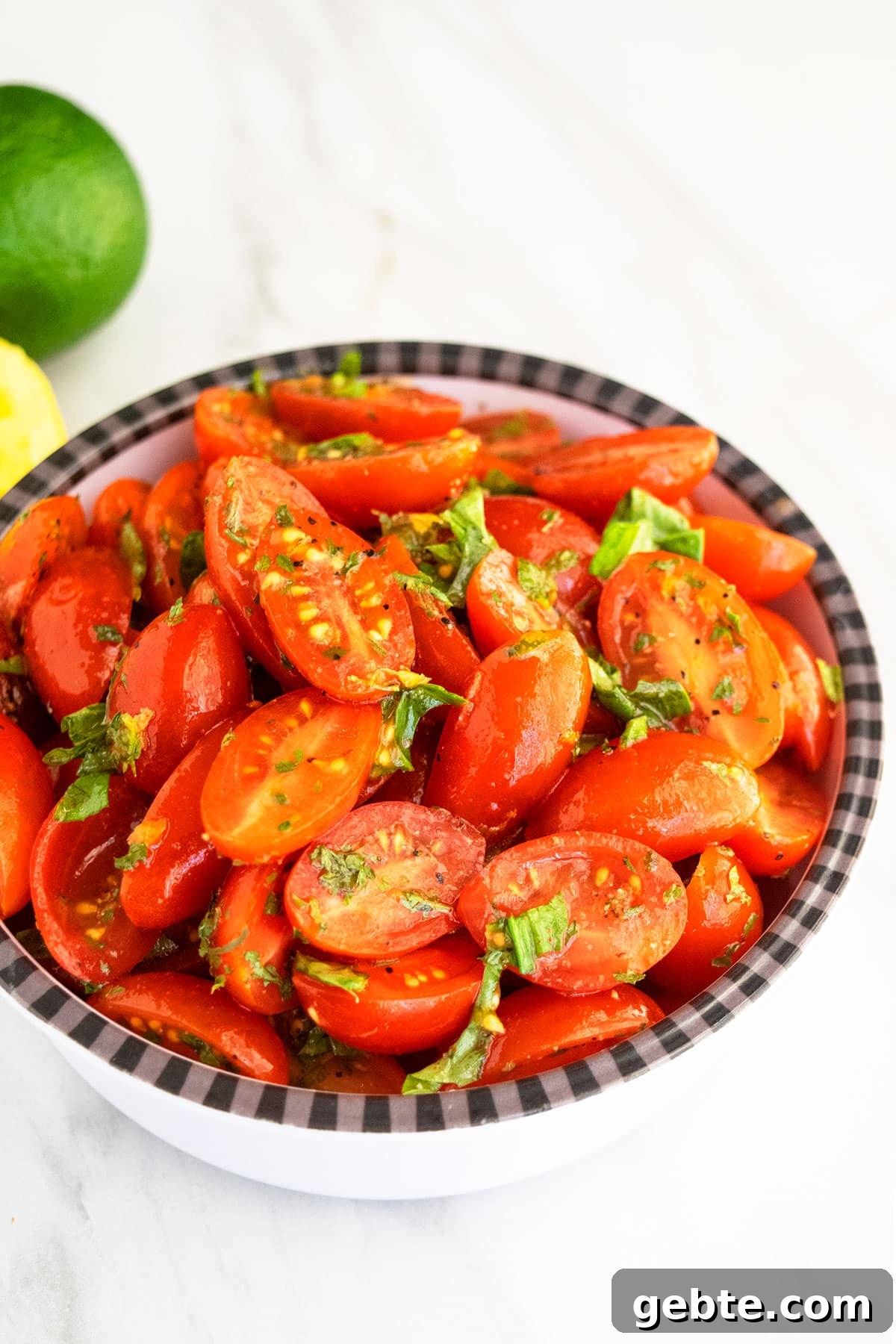 Cherry tomatoes and onions with herbs and spices in black and white bowl.
