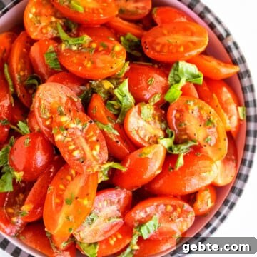 Best easy homemade marinated tomatoes with fresh herbs and spices in black and white bowl.