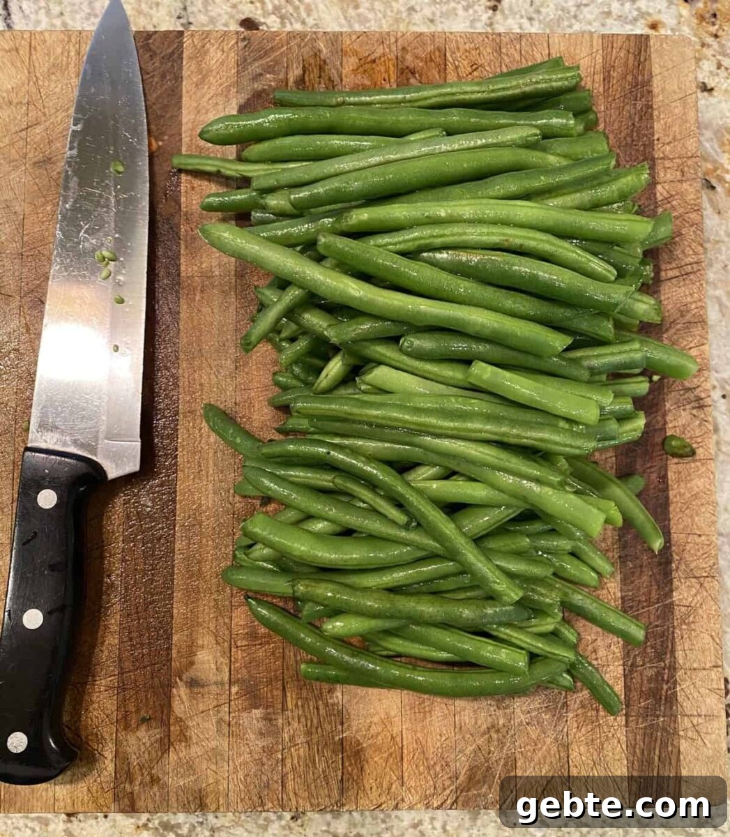 Green beans and a knife on a cutting board.