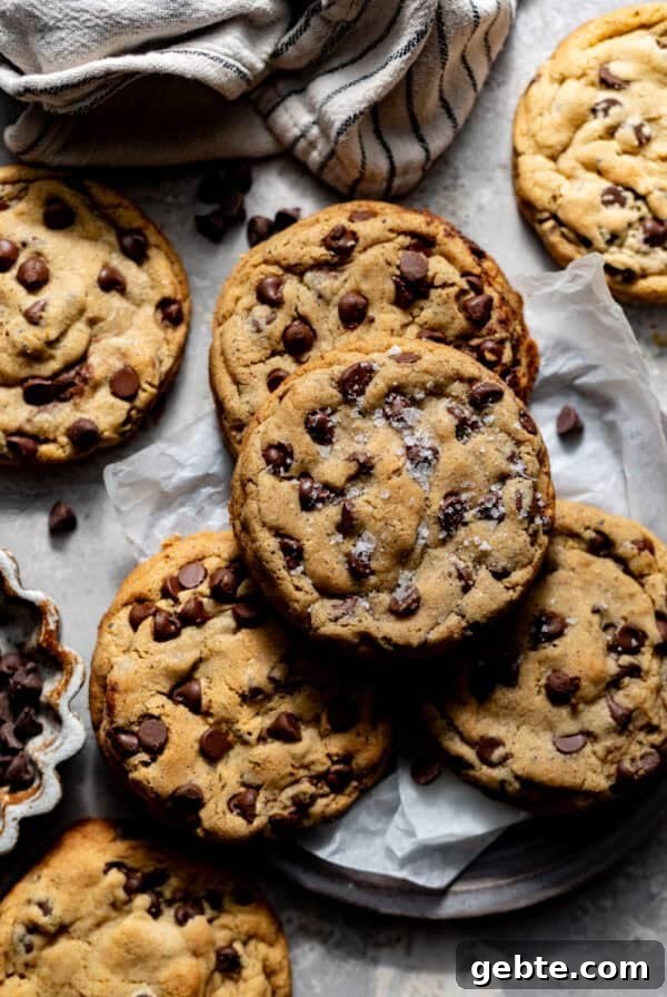 Crunchy Peppermint Chocolate Chip Cookies Recipe 14 brown butter cookies on a plate with parchment paper and topped with flaky salt.