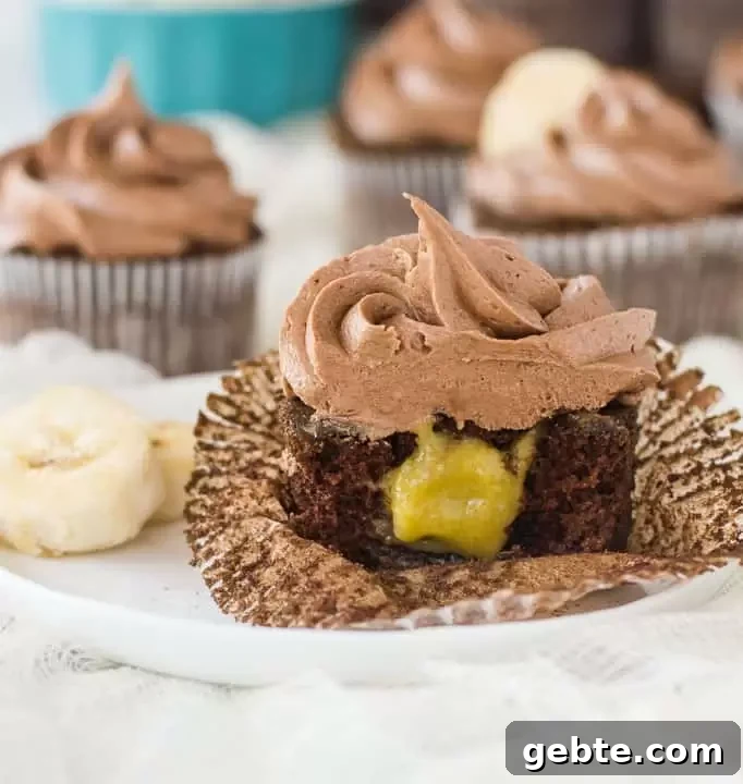 cupcake on a plate sliced in half to show the filling with more chocolate banana cupcakes in the background