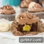 cupcake on a plate sliced in half to show the filling with more chocolate banana cupcakes in the background