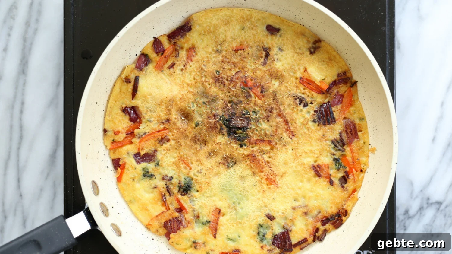 Mung Bean Egg Vegan Omelet: Fluffy Plant-Based Breakfast 11 Veggie filled Vegan Omelet on a white skillet