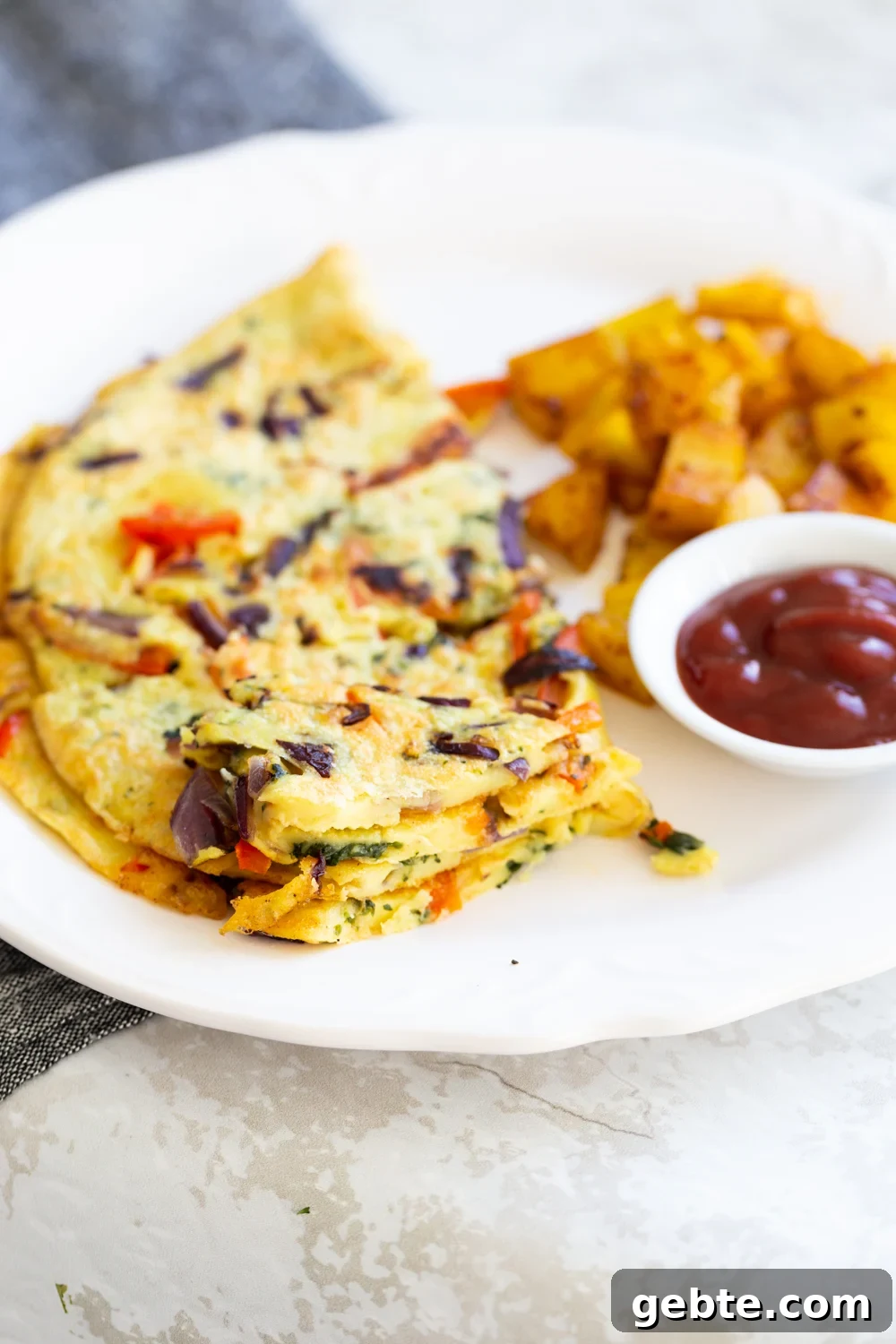 Mung Bean Egg Vegan Omelet: Fluffy Plant-Based Breakfast 15 Veggie Vegan Omelet on a white plate with potatoes and ketchup