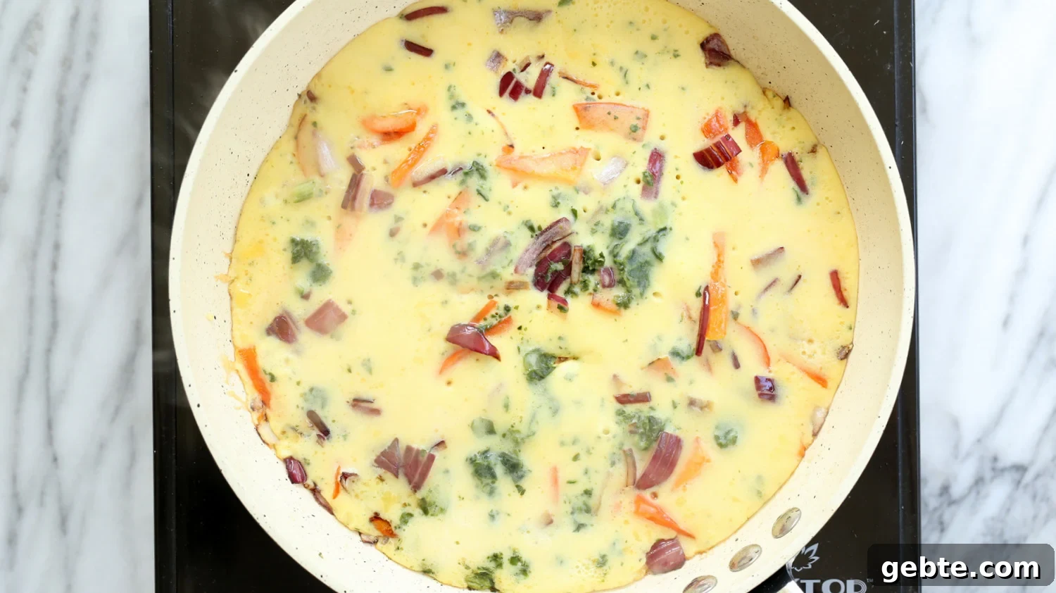 Mung Bean Egg Vegan Omelet: Fluffy Plant-Based Breakfast 10 Veggie filled Vegan Omelet on a white skillet