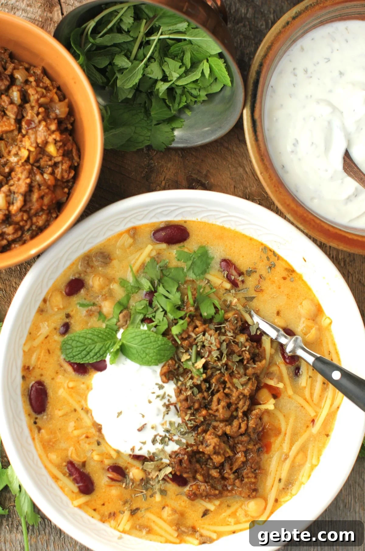top-down view of bowl of Aush with little bowls of toppings around it.