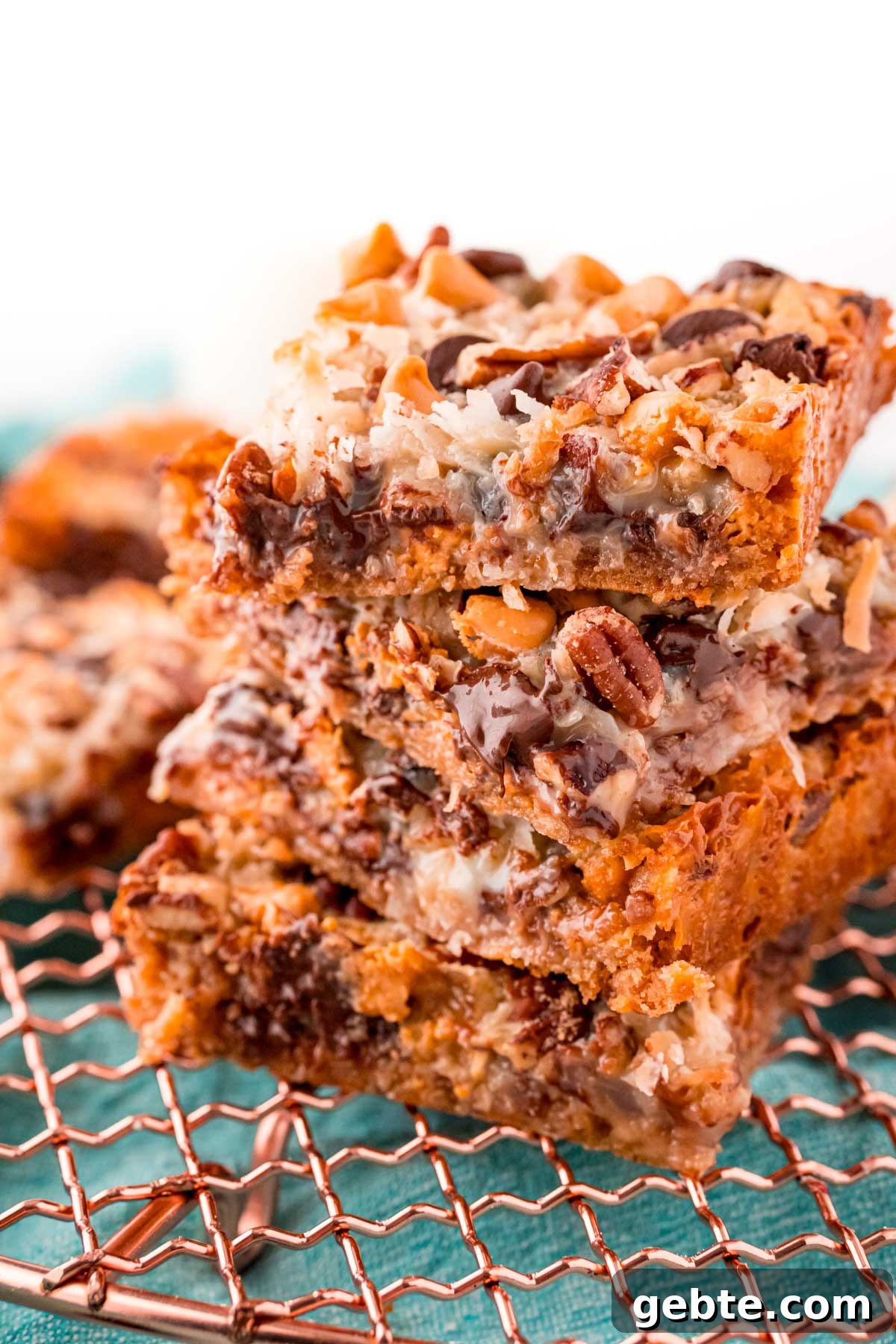 Classic Hello Dolly 7-Layer Cookie Bars Recipe 6 Close up photo of four hello dolly bars stacked on top of each other.