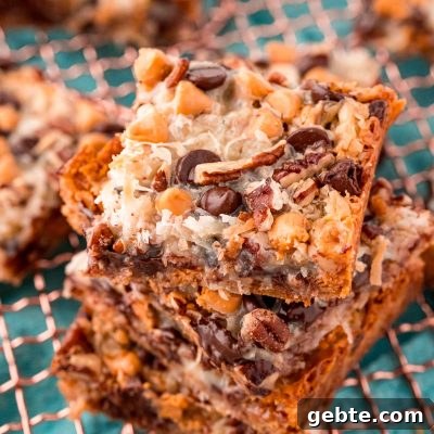 Classic Hello Dolly 7-Layer Cookie Bars Recipe 7 Close up photo of Hello Dolly Bars stacked on a copper wire rack.