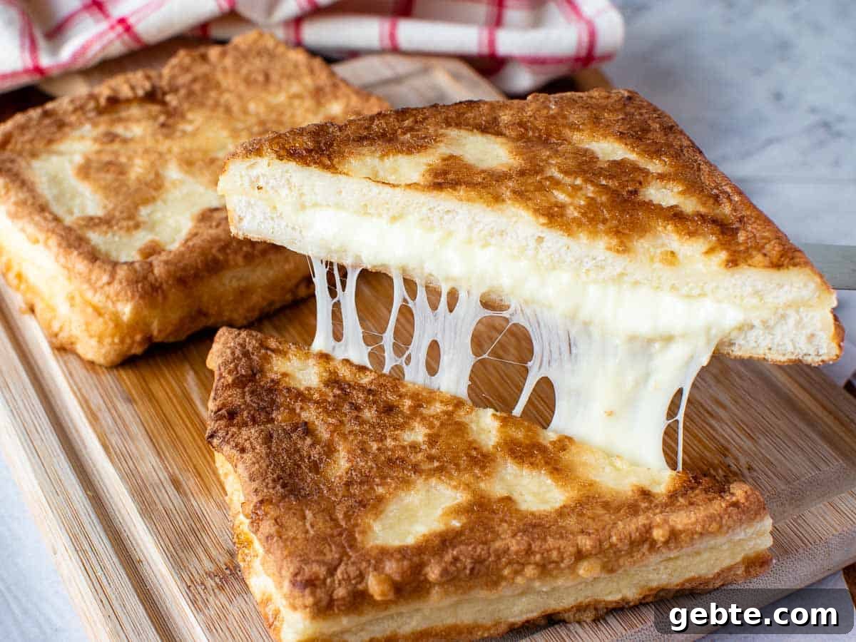 Crispy Mozzarella in Carrozza Sandwiches: Classic Italian Fried Cheese 8 Fried sandwich cut in half and showing cheese pull with second sandwich in background.