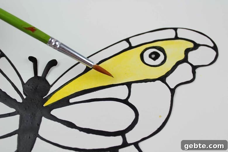 A paintbrush applying yellow paint to butterfly