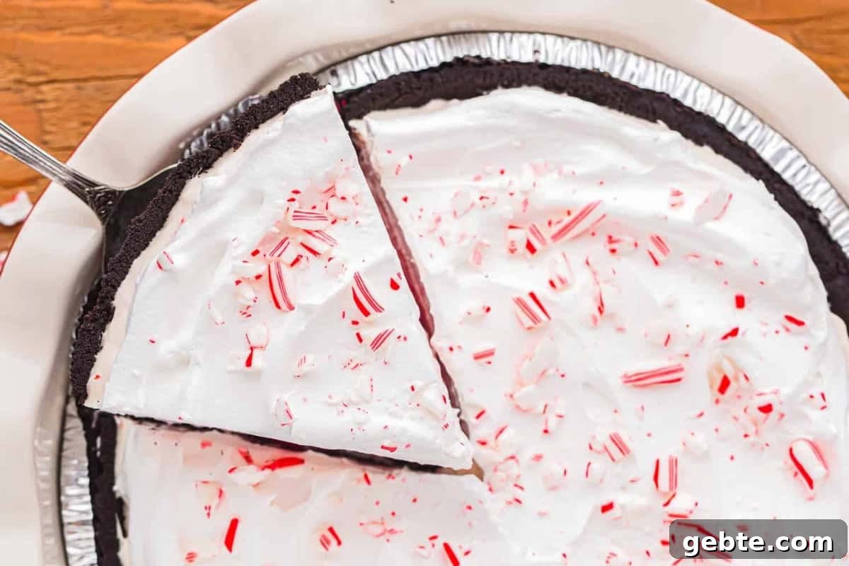 Classic Peppermint Pie Recipe — Cool Mint Dessert Guide 3 partial overhead view of a pie server lifting a slice of peppermint pie from a pie pan.