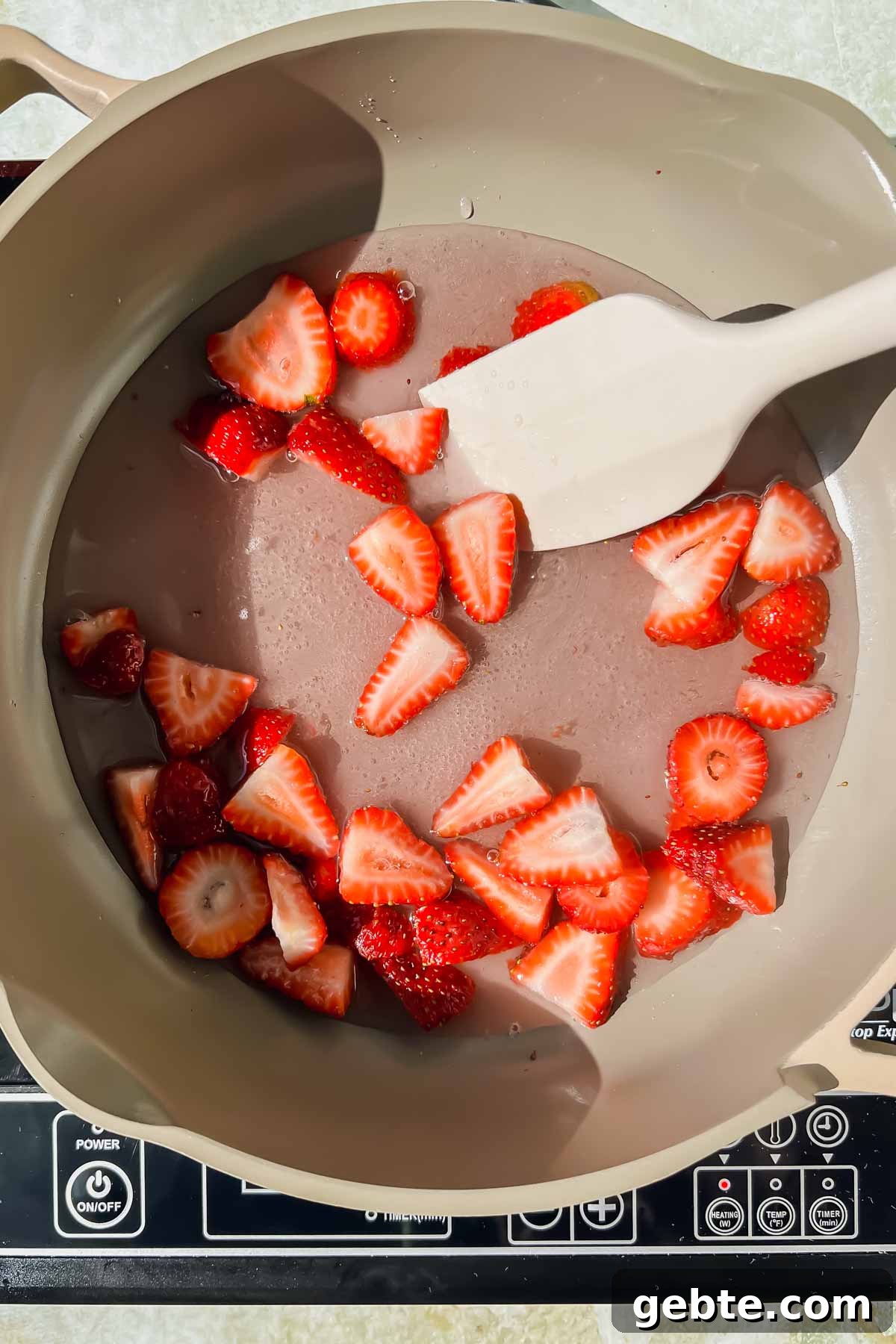 Strawberry Gin Smash: Refreshing Cocktail Recipe for Summer 4 strawberry halves, water, and sugar being heated in sauce pan to create simple syrup.