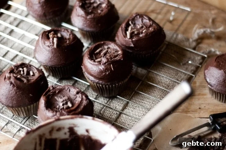 Chocolate cupcakes on a wire rack with chocolate buttercream and chocolate shavings on top 