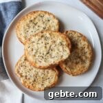 white plate with four slices of french bread topped with cheese, butter, and italian seasoning