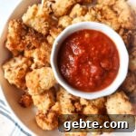 white bowl with air fryer cauliflower parmesan with warmed marinara in a cup