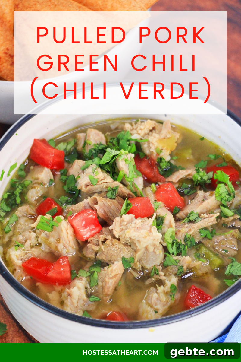 Savory Pulled Pork Green Chile (Chili Verde) Recipe 14 An image for Pinterest of a bowl of Pulled Pork Green Chili Verde garnished with cilantro and freshly chopped tomatoes - Hostess At Heart