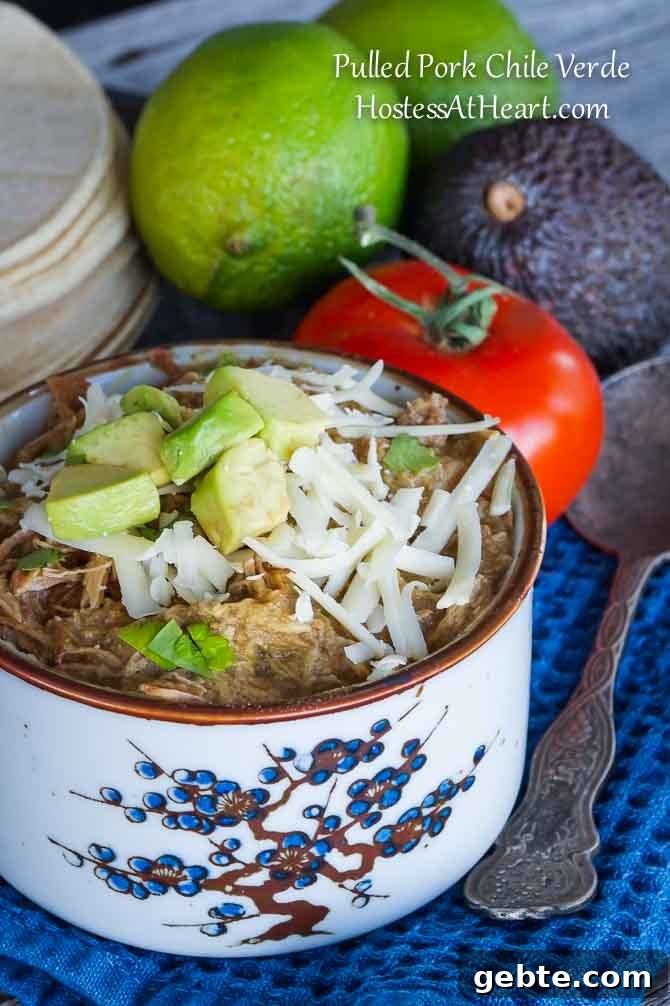 Savory Pulled Pork Green Chile (Chili Verde) Recipe 15 A bowl Pulled Pork Green Chile Verde surrounded by fresh lime, tomato, avocado, and tortillas.