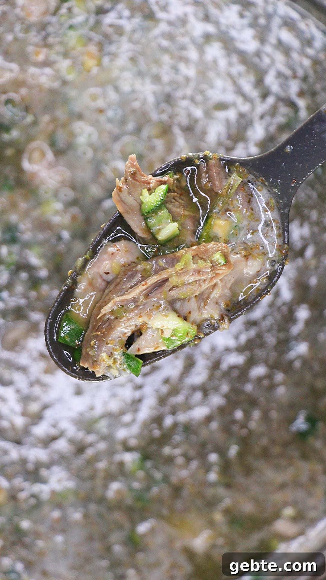 Savory Pulled Pork Green Chile (Chili Verde) Recipe 9 A spoon holding green chili pulled pork - Hostess At Heart