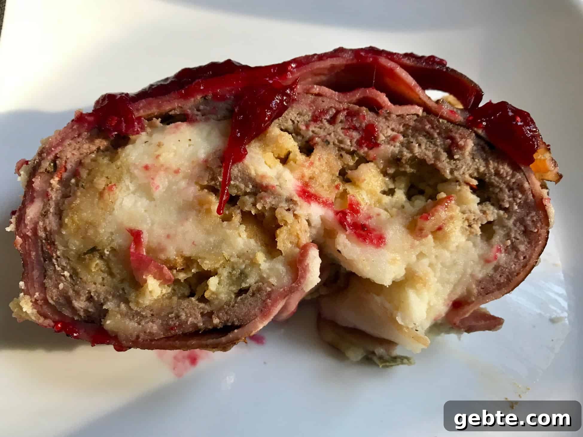 Thanksgiving Bacon Explosion Recipe for Holiday Brunch 3 Slice of Thanksgiving Bacon Explosion stuffed with stuffing and mashed potatoes close up view