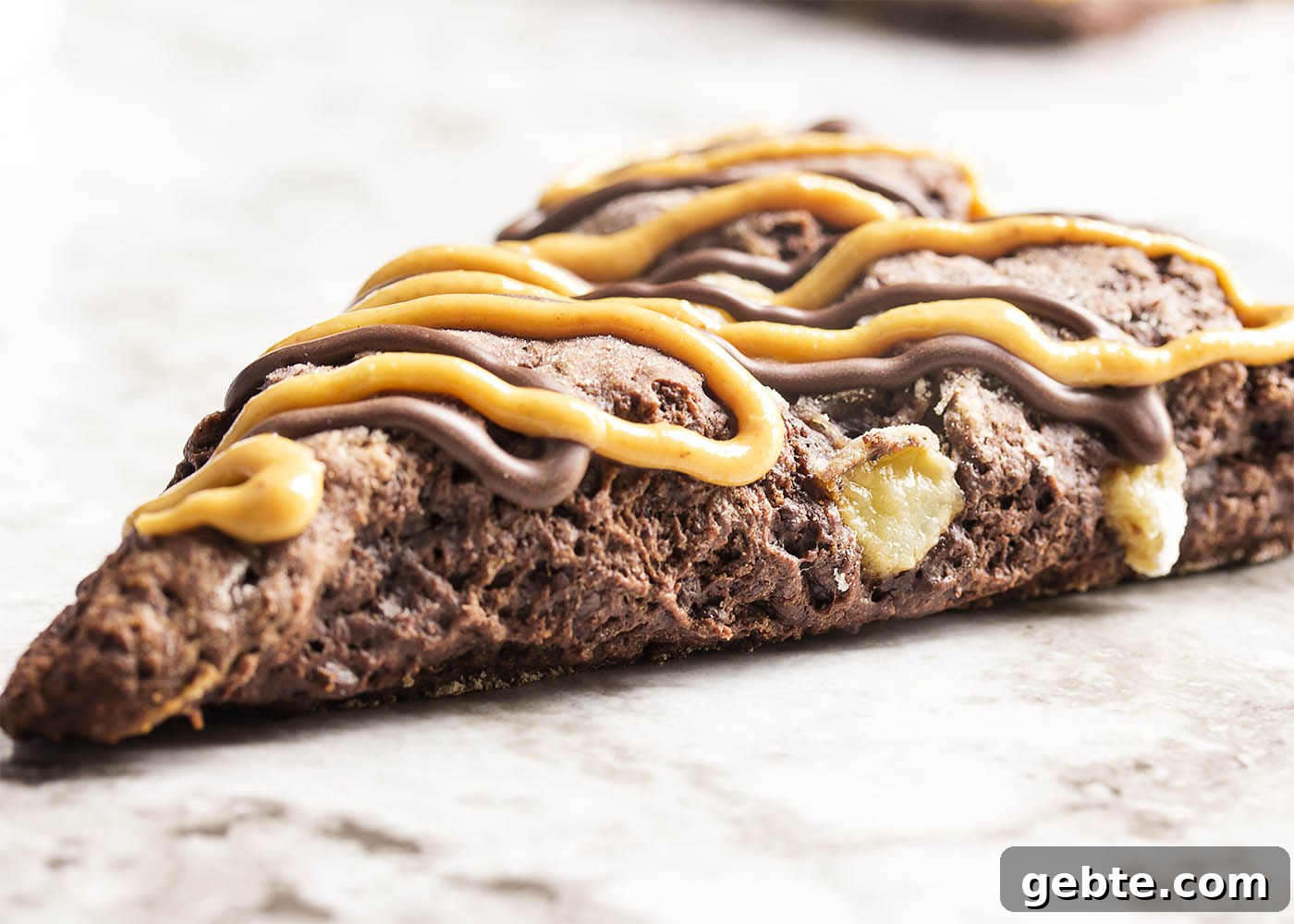 Triple Chocolate Banana Scones - These triple chocolate scones are studded with banana chunks in an intensely chocolatey batter and then topped with chocolate glaze and a peanut butter drizzle. Have them for breakfast or dessert and they would be perfect for a brunch.