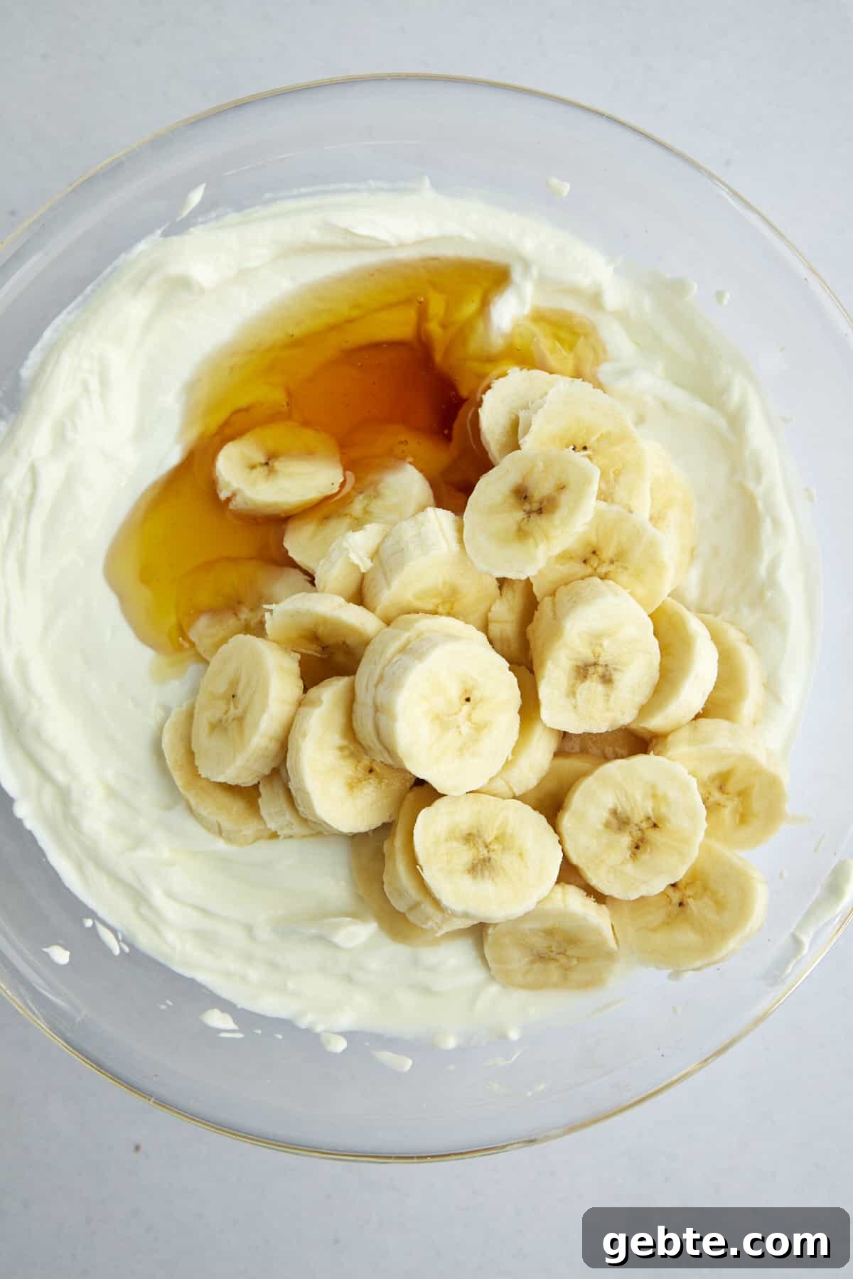 Overhead image of plain Greek yogurt, honey, and banana coins in a large mixing bowl. 
