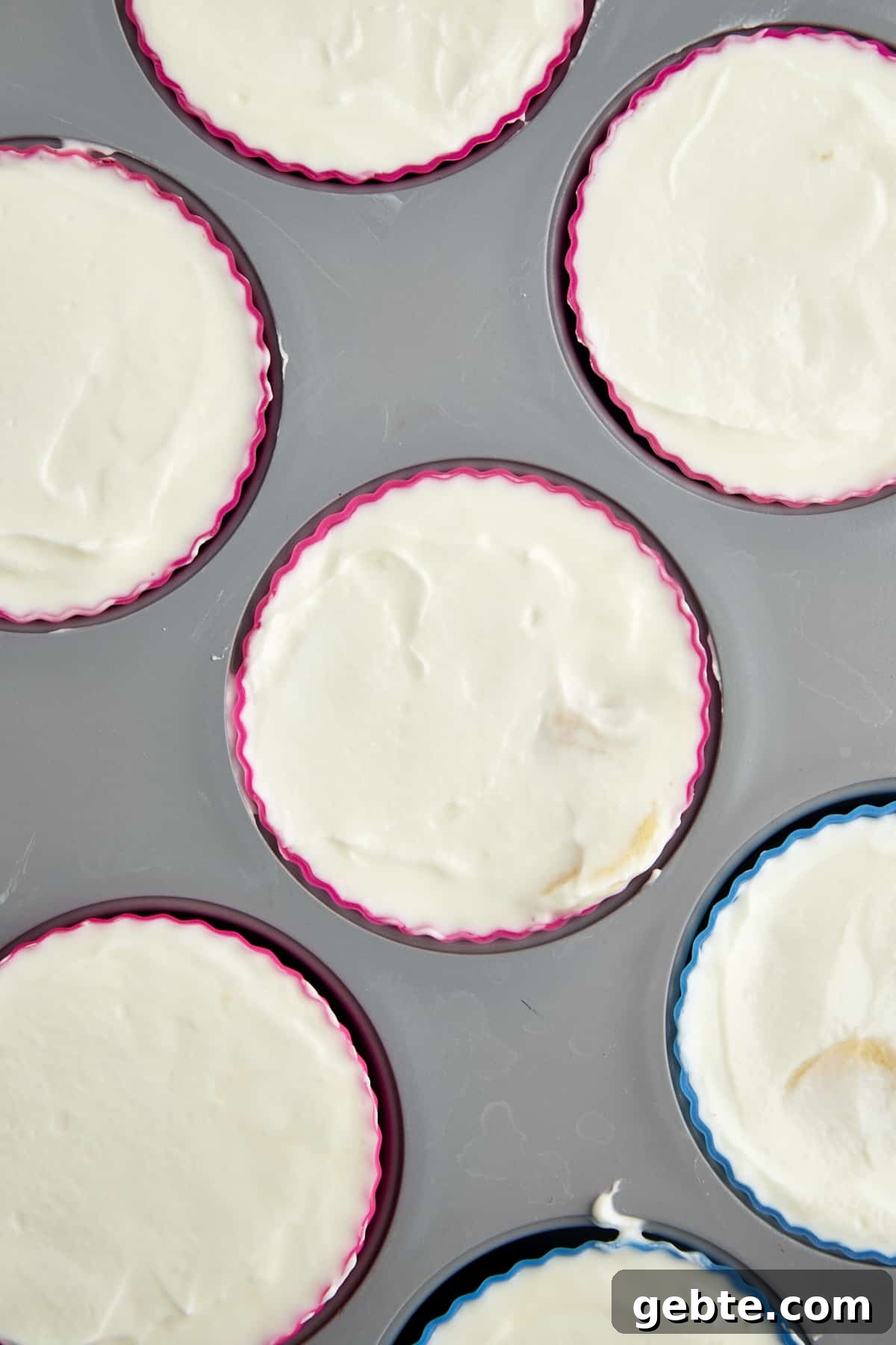 Overhead image of a yogurt, banana, and honey mixture in a silicone-lined mini muffin tin. 