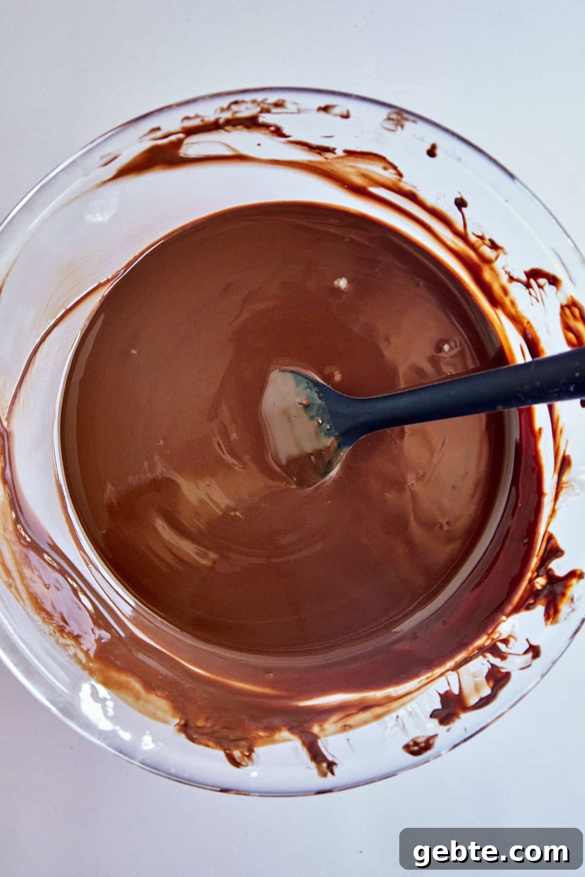Overhead image of a bowl of melted chocolate with a rubber spoon sticking out. 