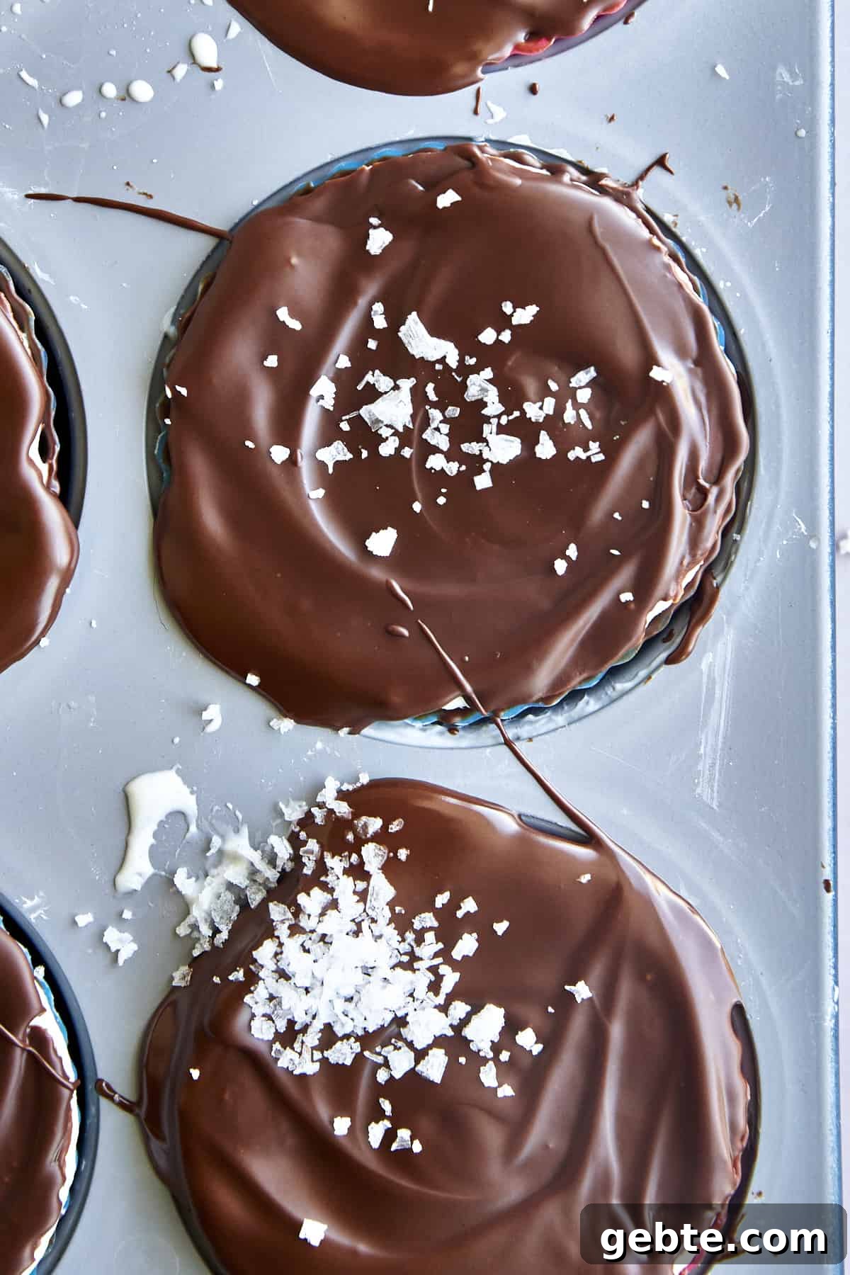 Chocolate coated frozen yogurt bites topped with se salt in a silicone-lined mini muffin tin. 