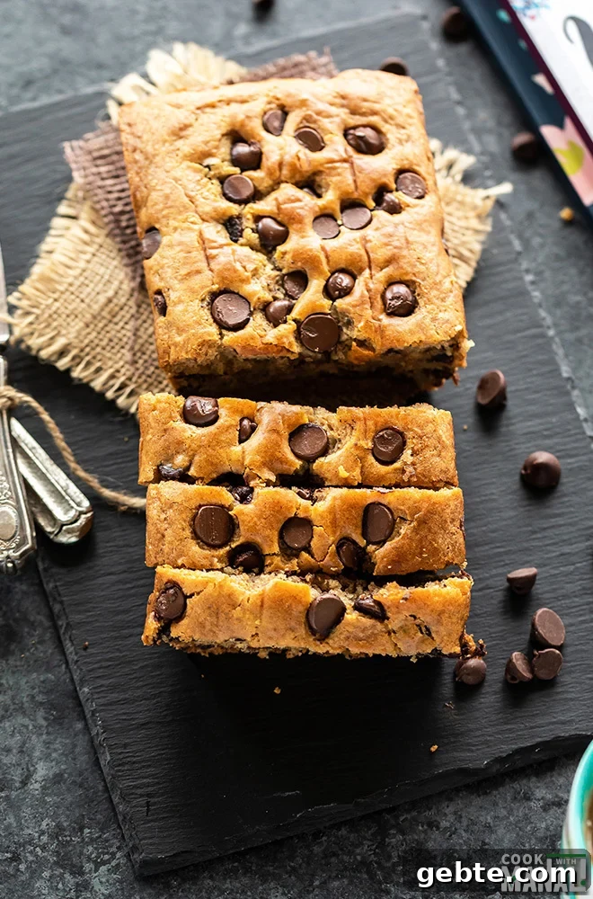 loaf of eggless chocolate chip cake placed on a black board and cut into 3 slices