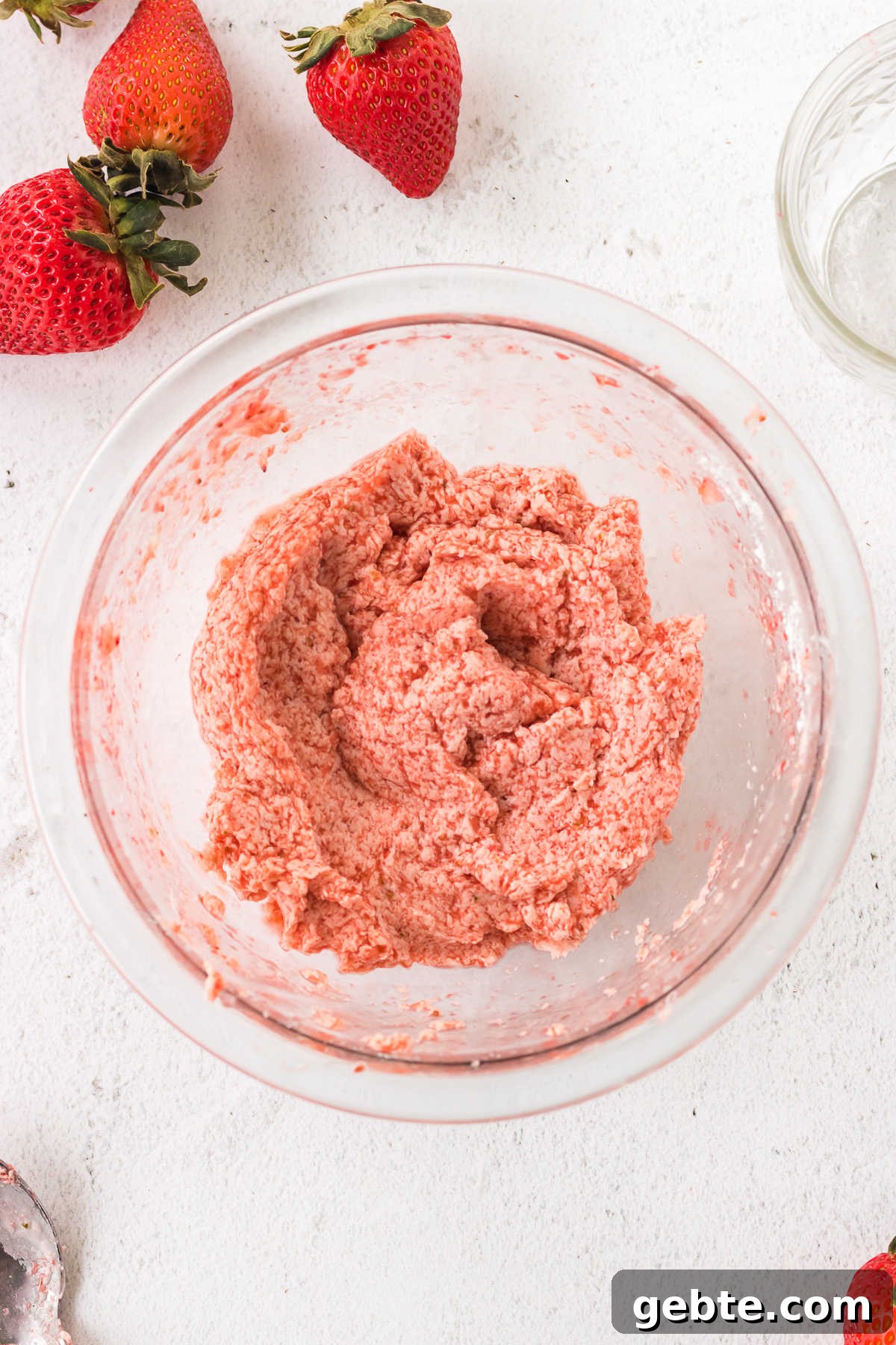 Overhead view of strawberry butter in a glass bowl.