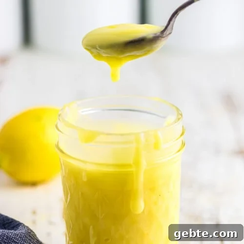 A spoonful of lemon curd being lifted from the jar.