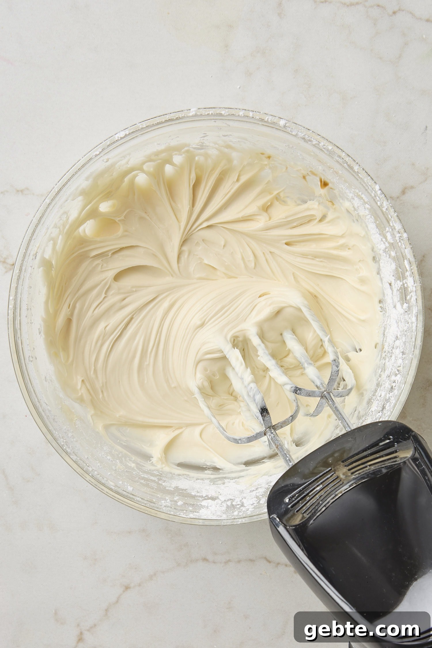 Glass bowl with cream cheese frosting after being mixed together.