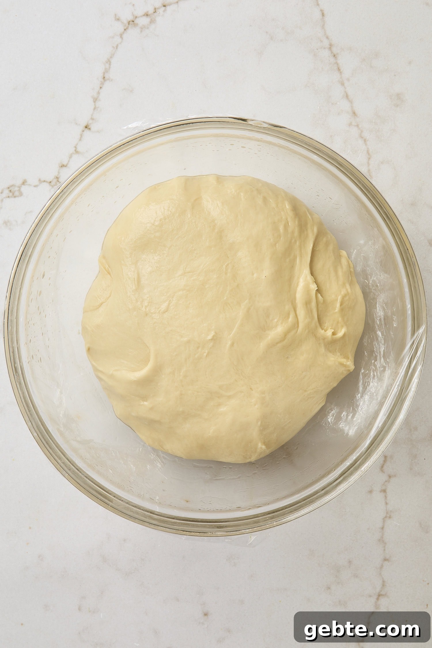 Glass bowl with dough after being kneaded with butter.