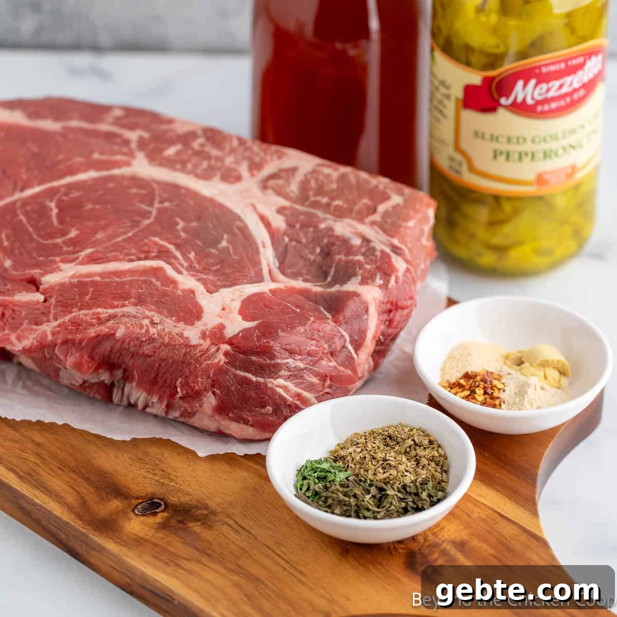 A chuck roast along with seasoning and pepperoncini peppers on a board. 