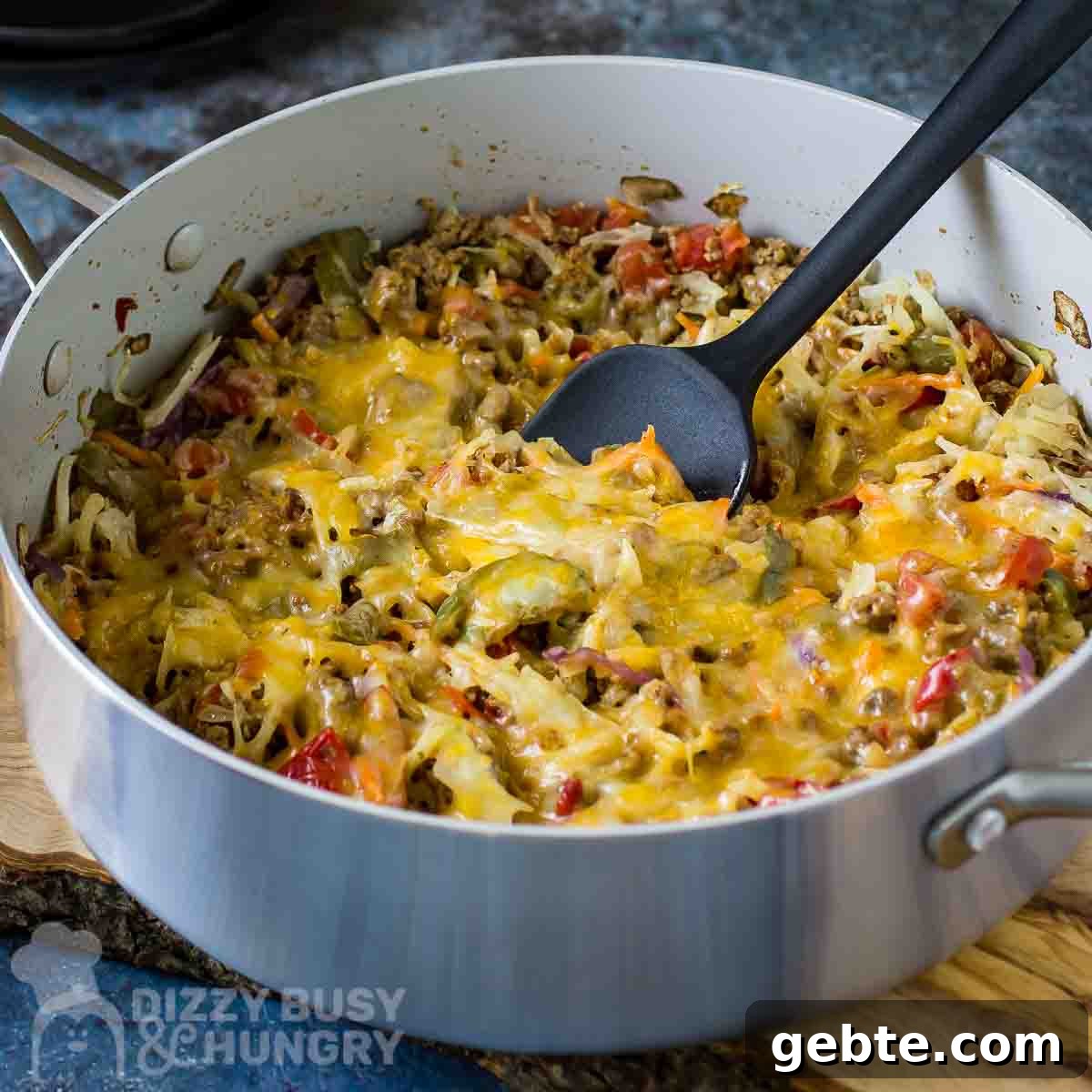 One-Skillet Stuffed Cabbage Casserole Recipe for Quick Weeknights 7 Side angled shot of cabbage casserole in a large shallow pot with a black spatula all resting on a wooden surface.
