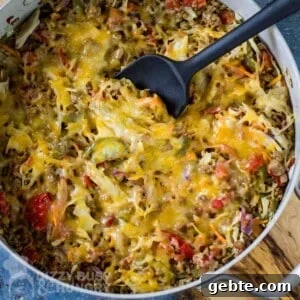 One-Skillet Stuffed Cabbage Casserole Recipe for Quick Weeknights 8 Overhead shot of cabbage casserole in a large shallow pot with a black spatula all resting on a wooden surface.