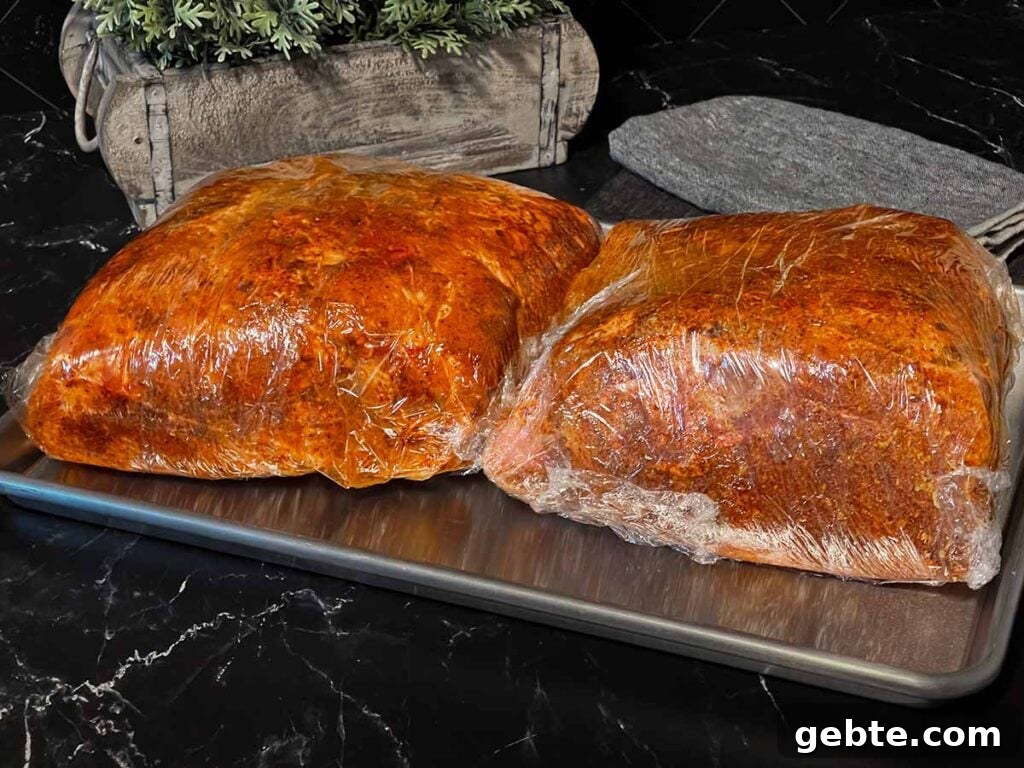 How to Smoke Pork Shoulder (Pork Butt) to Tender Perfection 6 Two pork butts with rub applied, wrapped in plastic wrap.