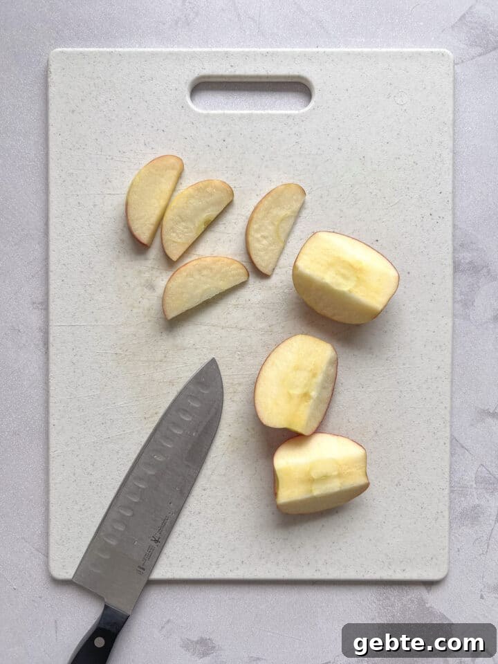 apple slices on a white cutting board with a knife placed next to them.