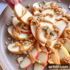 Healthy apple nachos on a plate with peanut butter and granola